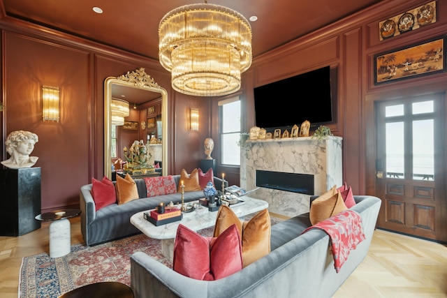 living room featuring an inviting chandelier, a fireplace, a decorative wall, and crown molding