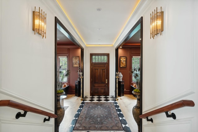 entryway featuring a raised ceiling and crown molding