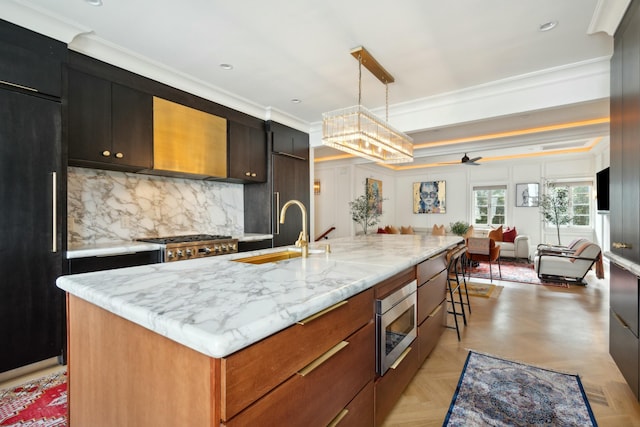 kitchen featuring stainless steel microwave, open floor plan, a large island with sink, high end black refrigerator, and a sink