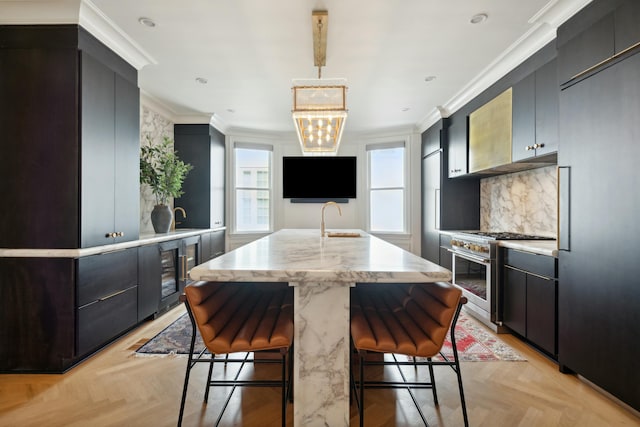 kitchen featuring a center island with sink, decorative backsplash, high end stainless steel range, crown molding, and a kitchen bar