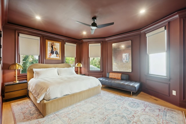 bedroom with multiple windows, wood finished floors, and a decorative wall