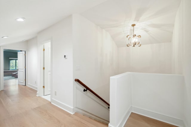 hall featuring baseboards, lofted ceiling, an upstairs landing, light wood-style floors, and recessed lighting