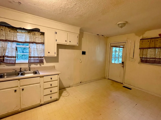 kitchen featuring sink, white cabinets, and a textured ceiling