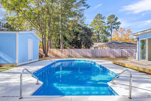 view of swimming pool featuring a deck and a storage shed