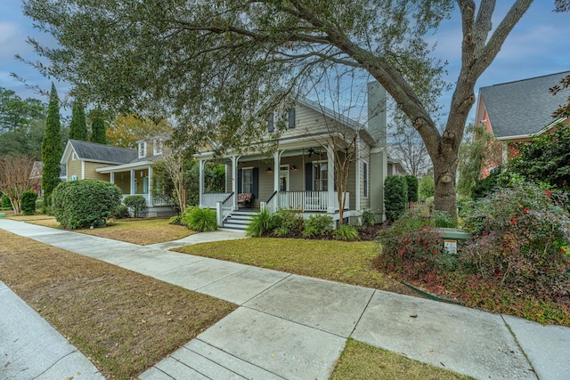 bungalow featuring covered porch and a front yard