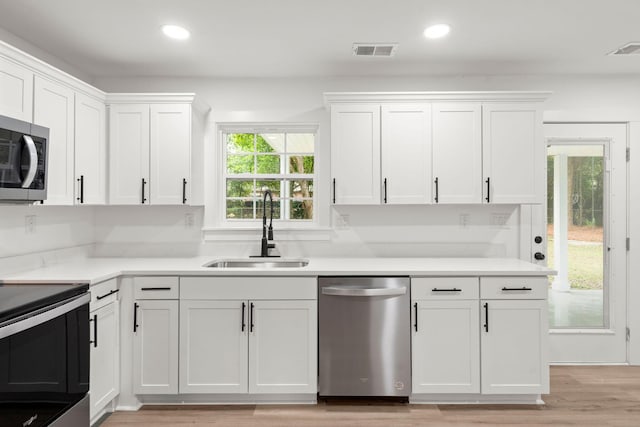 kitchen with white cabinetry, sink, stainless steel appliances, and light wood-type flooring