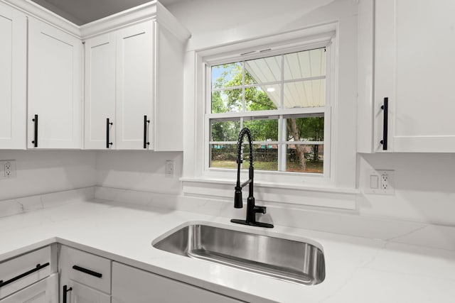 kitchen featuring white cabinetry, light stone countertops, and sink