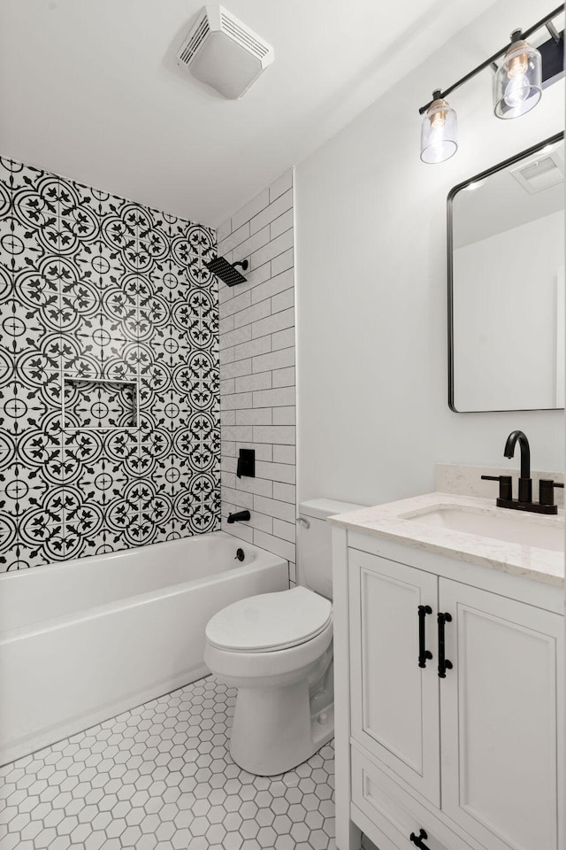 full bathroom with tile patterned flooring, tiled shower / bath, vanity, and toilet