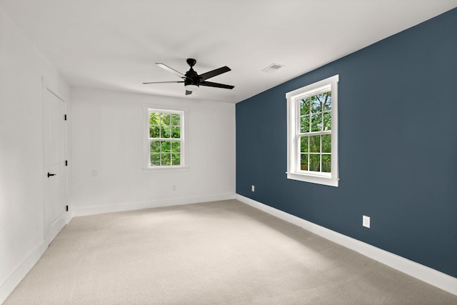 spare room with a healthy amount of sunlight, light carpet, and ceiling fan