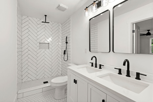 bathroom with ceiling fan, tiled shower, vanity, tile patterned floors, and toilet