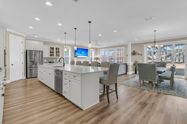 kitchen with white cabinets, visible vents, a center island with sink, appliances with stainless steel finishes, and a breakfast bar area