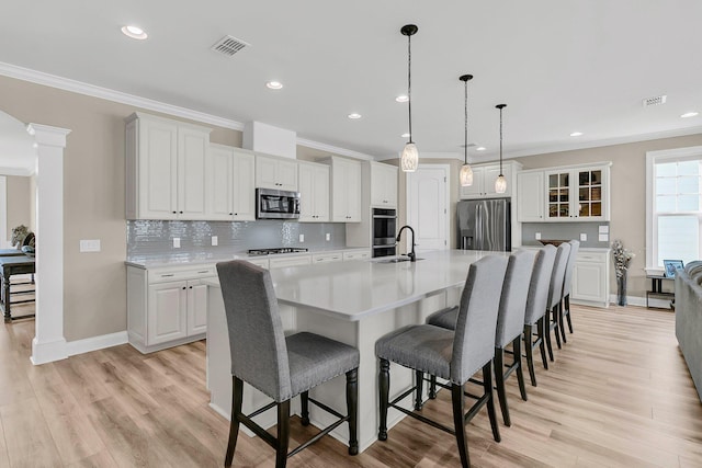 kitchen with visible vents, appliances with stainless steel finishes, white cabinetry, a sink, and a large island