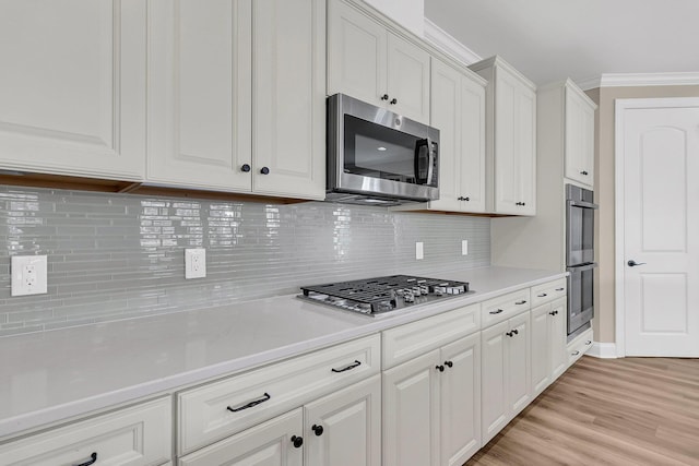 kitchen with white cabinetry, stainless steel appliances, light countertops, and light wood-type flooring