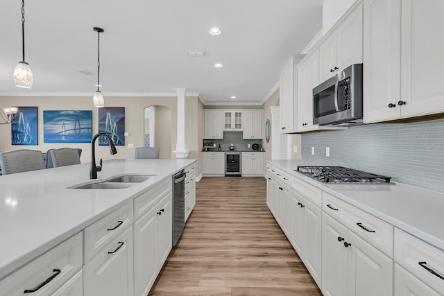 kitchen featuring ornamental molding, a sink, stainless steel appliances, and light countertops