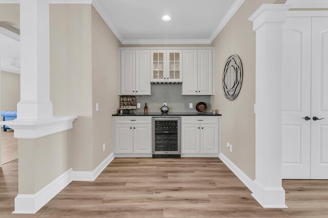 bar featuring beverage cooler, crown molding, tasteful backsplash, and indoor bar
