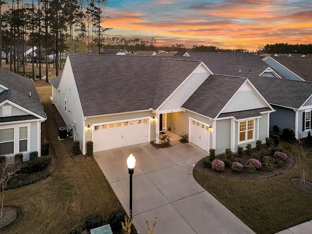 view of front facade with central AC unit, a garage, concrete driveway, a front lawn, and a shingled roof