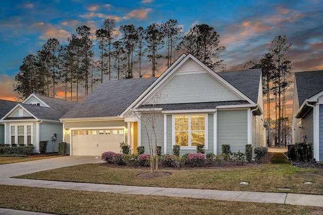 view of front facade with concrete driveway, a garage, a yard, and a shingled roof