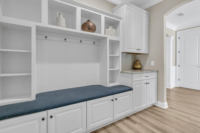 mudroom featuring visible vents, light wood finished floors, baseboards, ornamental molding, and arched walkways