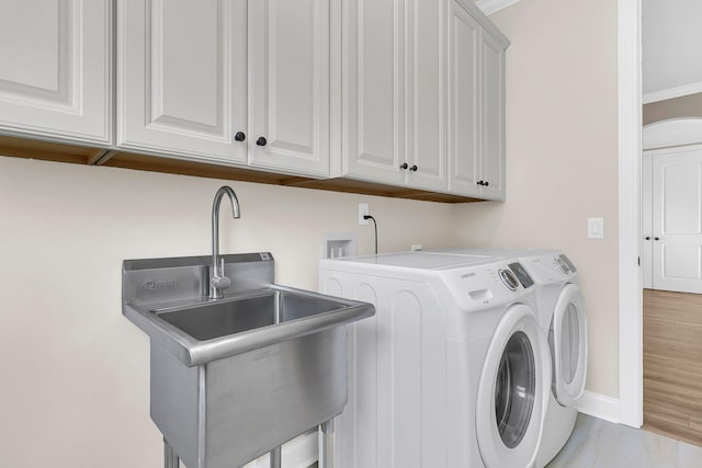 laundry area featuring baseboards, ornamental molding, a sink, washer and dryer, and cabinet space