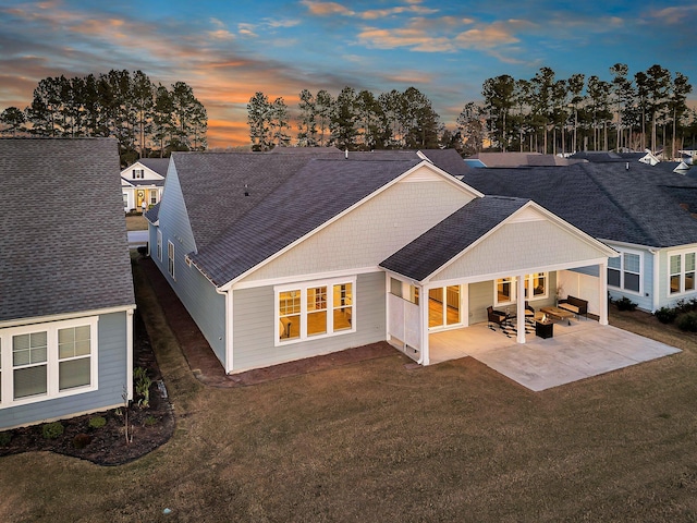 back of property featuring a patio, a shingled roof, and a yard