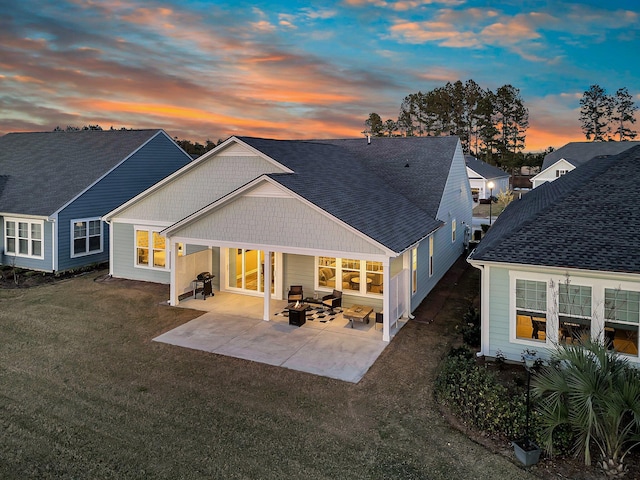 rear view of house featuring a patio, a lawn, and roof with shingles
