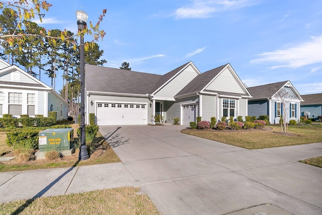 view of front of house with an attached garage, a shingled roof, concrete driveway, and a front yard