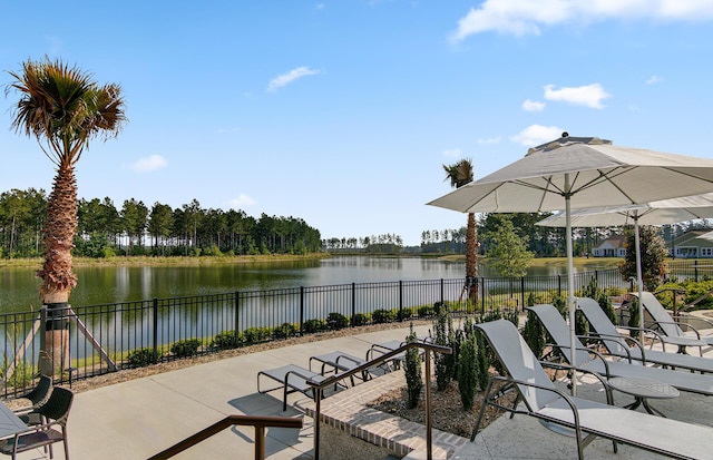 view of patio featuring a water view and fence