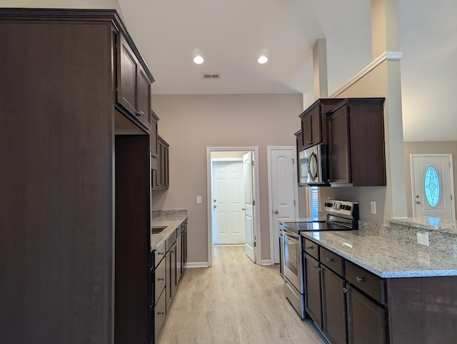 kitchen featuring stainless steel appliances, light hardwood / wood-style floors, dark brown cabinetry, and light stone counters