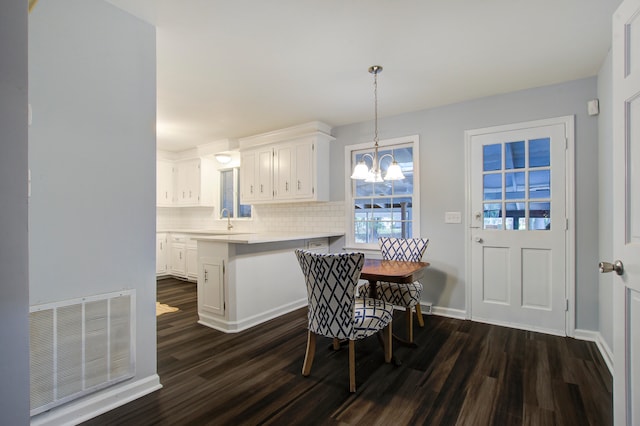 dining area with a chandelier, dark wood-type flooring, and sink