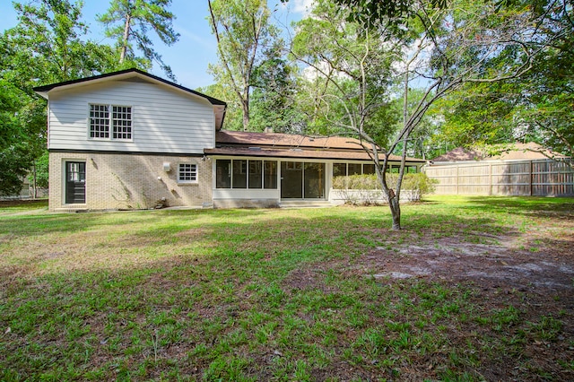 rear view of property featuring a sunroom and a lawn