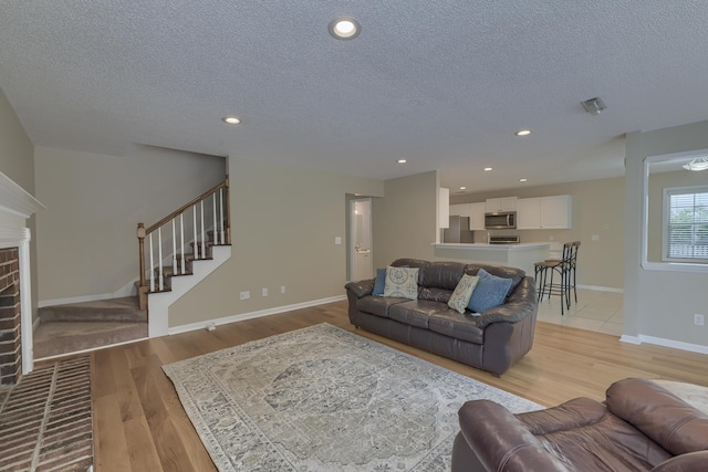 1616 Dotterers Run, Charleston, SC 29414 - living room featuring a textured ceiling, stairs, light wood-type flooring, a brick fireplace, and recessed lighting