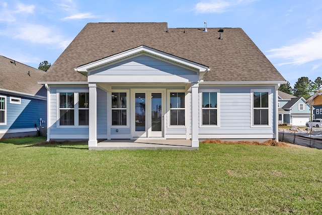 back of property featuring roof with shingles and a yard