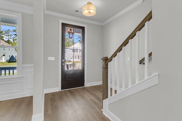 foyer featuring wood finished floors, stairway, and ornamental molding