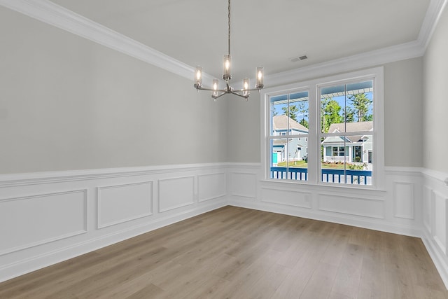 spare room featuring ornamental molding, an inviting chandelier, visible vents, and a wainscoted wall