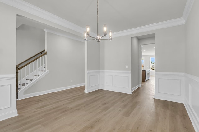 unfurnished dining area with stairs, light wood-style floors, an inviting chandelier, and wainscoting