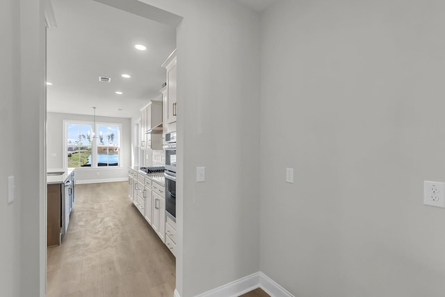 kitchen with light wood finished floors, baseboards, light countertops, and white cabinets