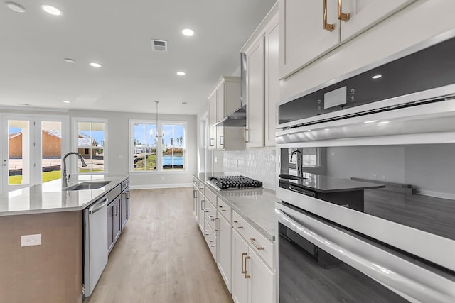 kitchen featuring a sink, stainless steel appliances, white cabinets, light wood-type flooring, and visible vents