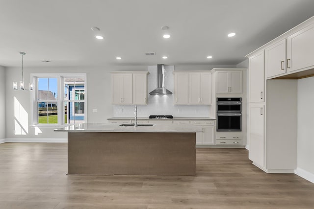 kitchen with stainless steel double oven, a sink, decorative backsplash, wall chimney exhaust hood, and light countertops