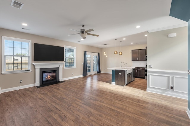 unfurnished living room featuring hardwood / wood-style flooring, ceiling fan, and sink