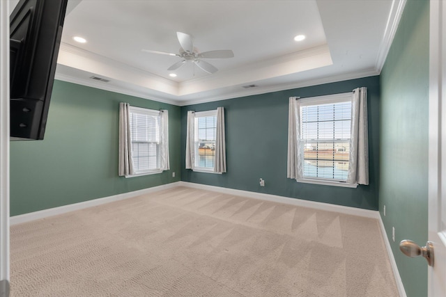 unfurnished room featuring a tray ceiling, light carpet, ceiling fan, and ornamental molding