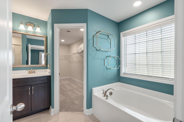 bathroom with tile patterned floors, a washtub, and vanity