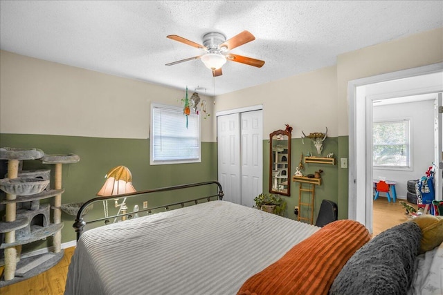 bedroom with a closet, light hardwood / wood-style flooring, multiple windows, and ceiling fan