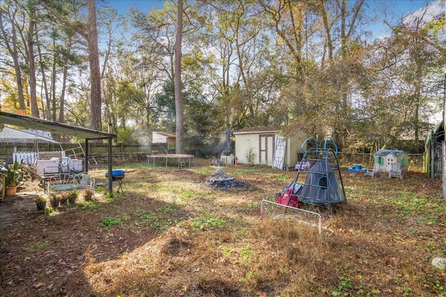 view of yard with a carport, a trampoline, and a storage unit