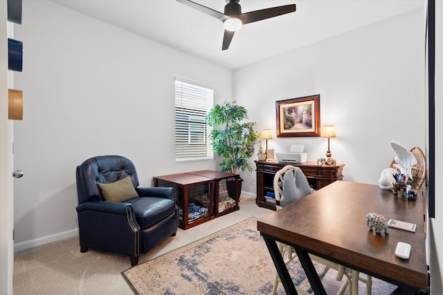 carpeted office with a ceiling fan and baseboards