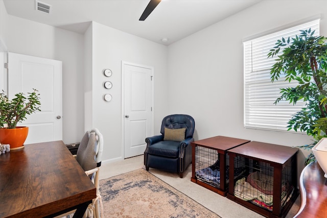 office area featuring light colored carpet, visible vents, and a ceiling fan