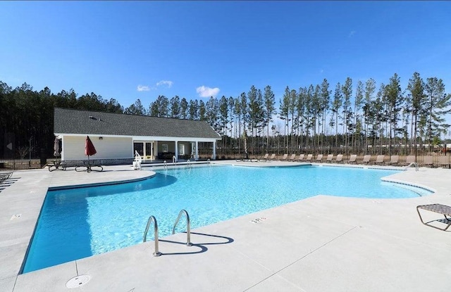 pool with a patio area and fence