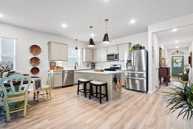 kitchen featuring light wood finished floors, a center island, gray cabinets, stainless steel appliances, and light countertops