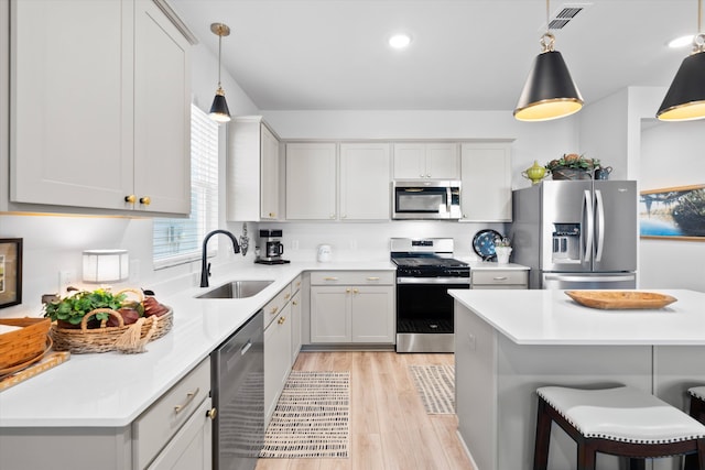 kitchen featuring light countertops, visible vents, appliances with stainless steel finishes, a sink, and a kitchen bar