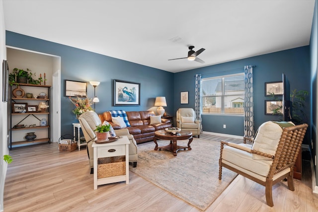 living area with light wood finished floors, baseboards, and a ceiling fan