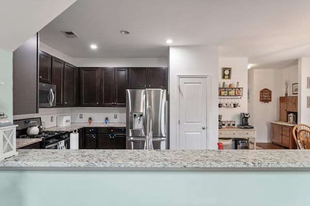 kitchen with light stone countertops, appliances with stainless steel finishes, kitchen peninsula, and decorative backsplash